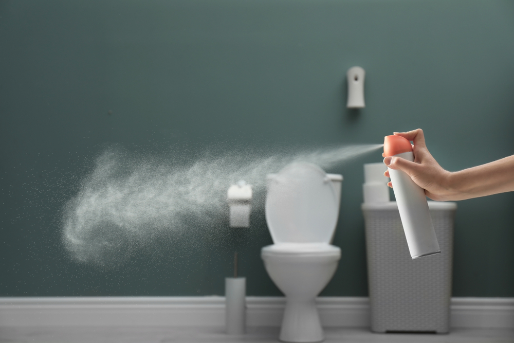 ผู้หญิงกำลังฉีดสเปรย์เพื่อกำจัดกลิ่นอับในห้องน้ำ